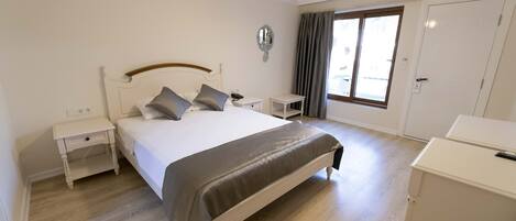 Une chambre à coucher avec un lit, des tables de chevet, une armoire et une fenêtre avec des rideaux.
