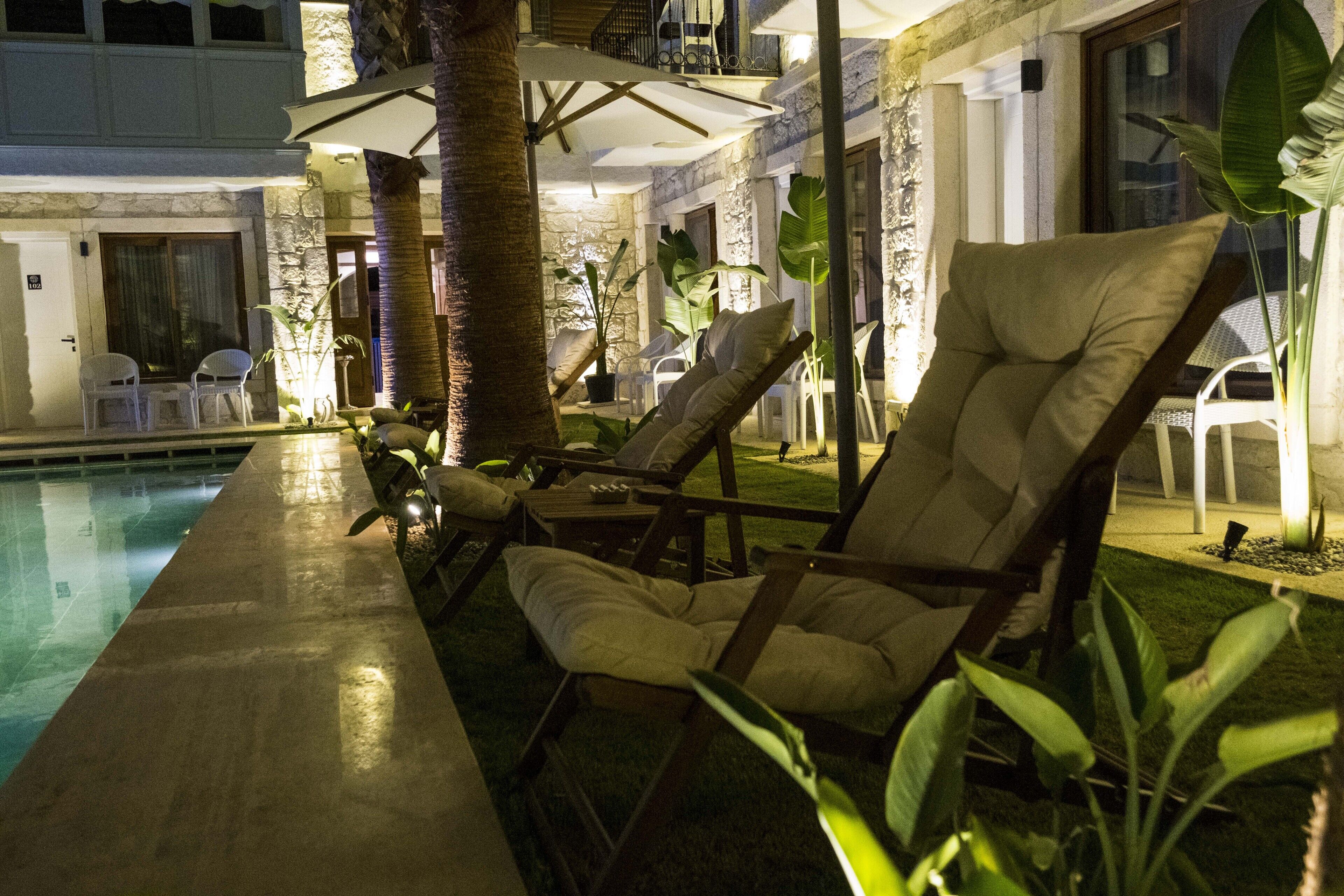 A poolside area with lounge chairs, a table, and umbrellas.