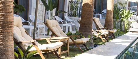 A poolside area with lounge chairs, a pool, and tropical plants.