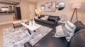 A modern living room with a black leather sofa, white coffee table, and a patterned rug. - New Pool/Spa & Pool Table @ 6BR Refined Vegas Stay (North Las Vegas)