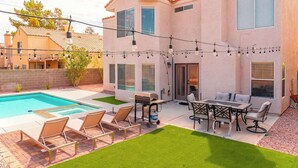 A two-story house with a swimming pool, outdoor seating area, and string lights. - New Pool/Spa & Pool Table @ 6BR Refined Vegas Stay (North Las Vegas)