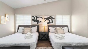 Une chambre d’hôtel avec deux lits, une table de chevet, une lampe et des œuvres d’art accrochées au mur.