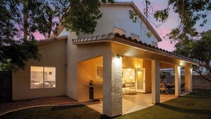 Une maison dotée d’un patio couvert, d’un barbecue et d’une pelouse bien entretenue.