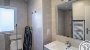 A modern bathroom with a large mirror, a bathtub, and a shower area.