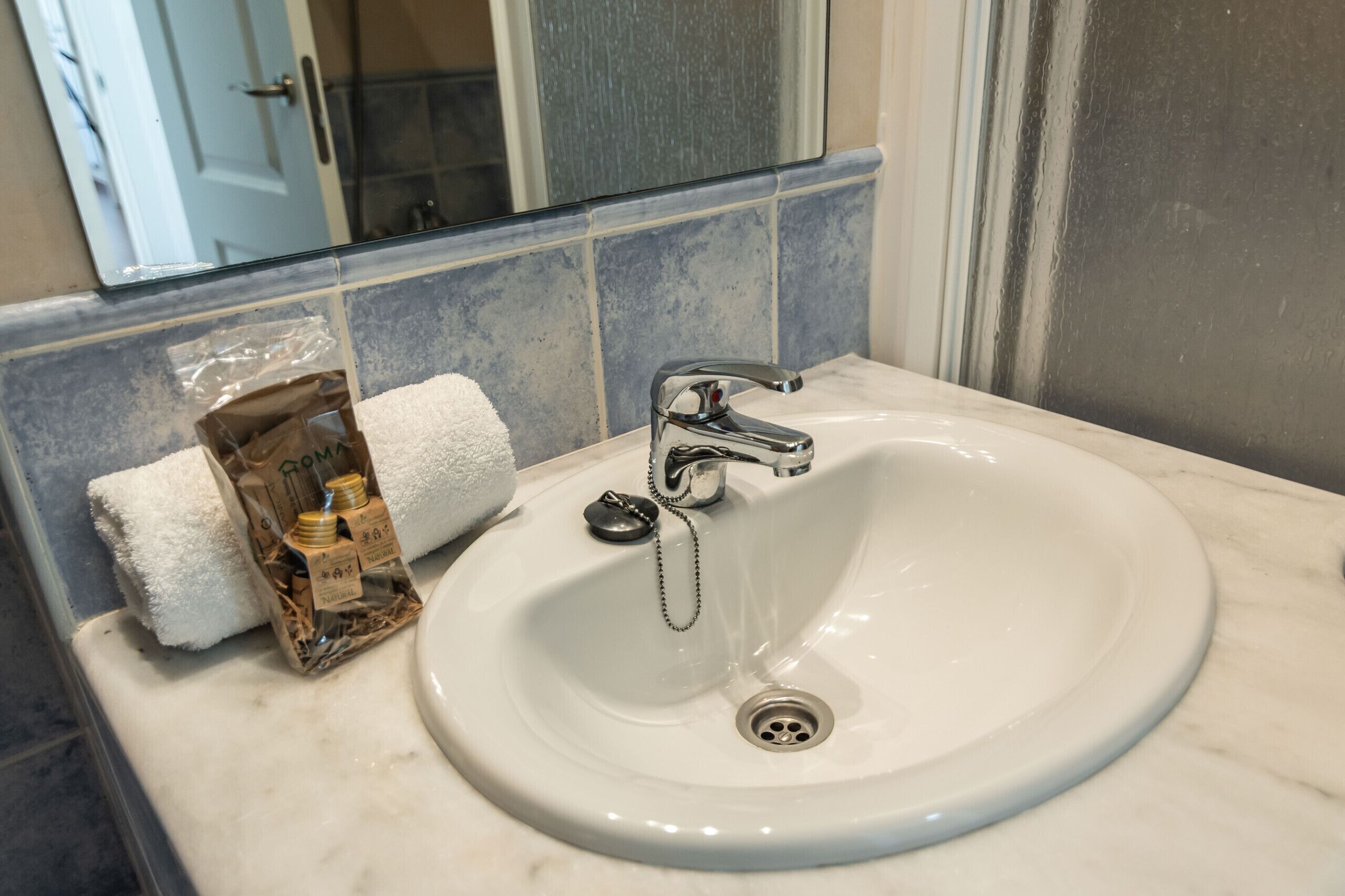 A bathroom sink with a mirror above it, a towel, and a bottle of hand soap.