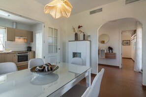 A modern kitchen with white cabinets, a glass dining table, and a hanging light fixture. - Albatros Golf I - Costa Esuri EAHGI173AP111 (Ayamonte)
