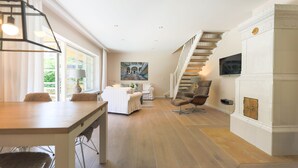 A spacious living area with a dining table, sofas, a fireplace, and a staircase. - Reethüs - Keitum (Keitum)