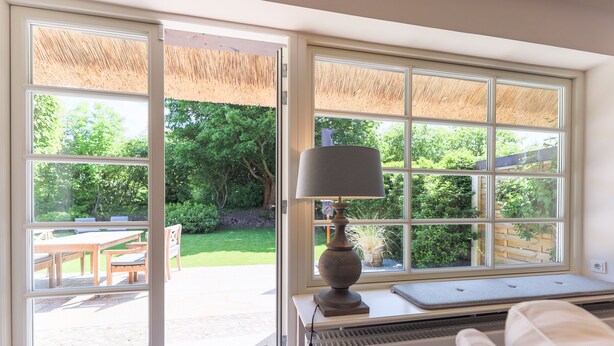 A room with a large window, a table, and a chair outside, and a radiator inside. - Reethüs - Keitum (Keitum)