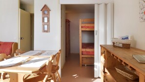 A cozy room with a wooden table, chairs, a bunk bed, and a wall clock. - Divisible studio 4 pers, ski-in/ski-out, pets allowed (Plagne Bellecôte)