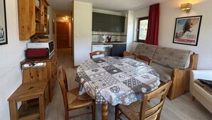 A cozy, compact living space with a dining area, kitchenette, and a sofa.
