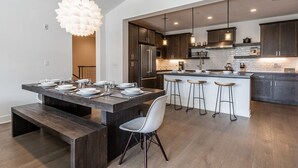A modern kitchen with dark wood cabinets, a central island with stools, and pendant lighting. - Eagle Lodge Shuttle | Mountain Views (Mammoth Lakes)