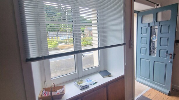 A room with a large window, a wooden bench with books, and a blue door. - Small house on the marina. (Pontrieux)