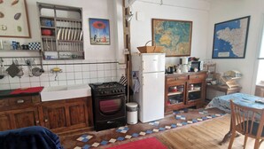 A cozy kitchen with a stove, sink, and refrigerator, wooden cabinets, and a dining area with a table and chairs. - Small house on the marina. (Pontrieux)