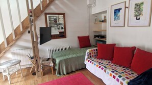 A cozy room with a loft bed, a red sofa, and a wooden staircase. - Small house on the marina. (Pontrieux)