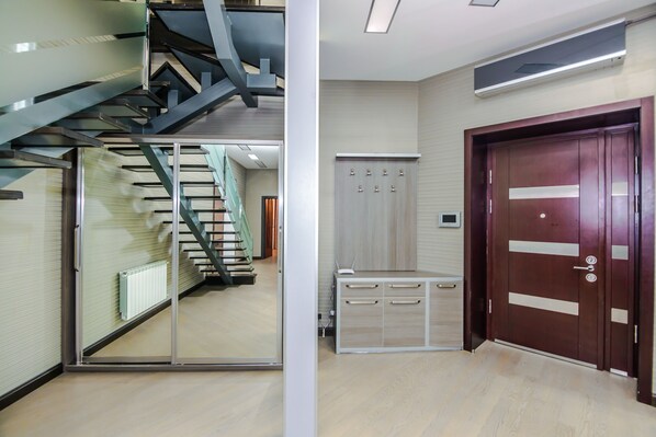 A modern interior with a staircase, a wooden door, and a small cabinet.
