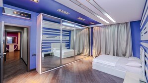 A modern hotel room with a sliding glass door, a white sofa, and a large mirror.
