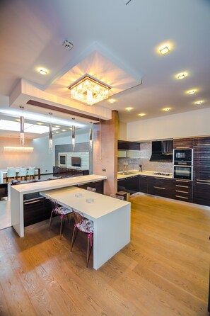 A modern kitchen with a central island, wooden flooring, and contemporary lighting fixtures.