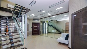 A modern interior with a staircase, a white sofa, and a glass wall reflecting a staircase.