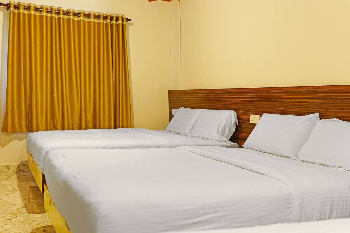 A hotel room with two beds, a wooden headboard, and a yellow curtain.