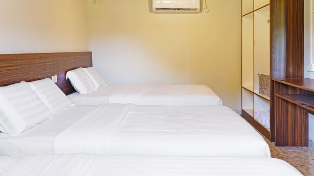 A hotel room with two beds, a wooden headboard, a built-in wardrobe, and an air conditioning unit. - Capital O 90557 Dedsaan Beach Village (Kota Belud)