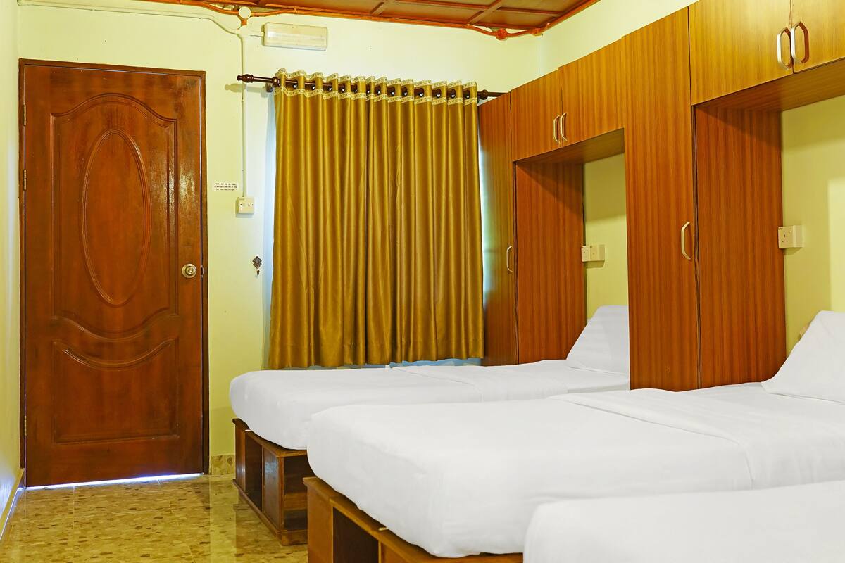 A room with two beds, a wooden wardrobe, a door, and a curtain.