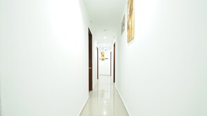 A long, narrow hallway with white walls and a shiny floor, leading to a door at the end. - Capital O 90557 Dedsaan Beach Village (Kota Belud)