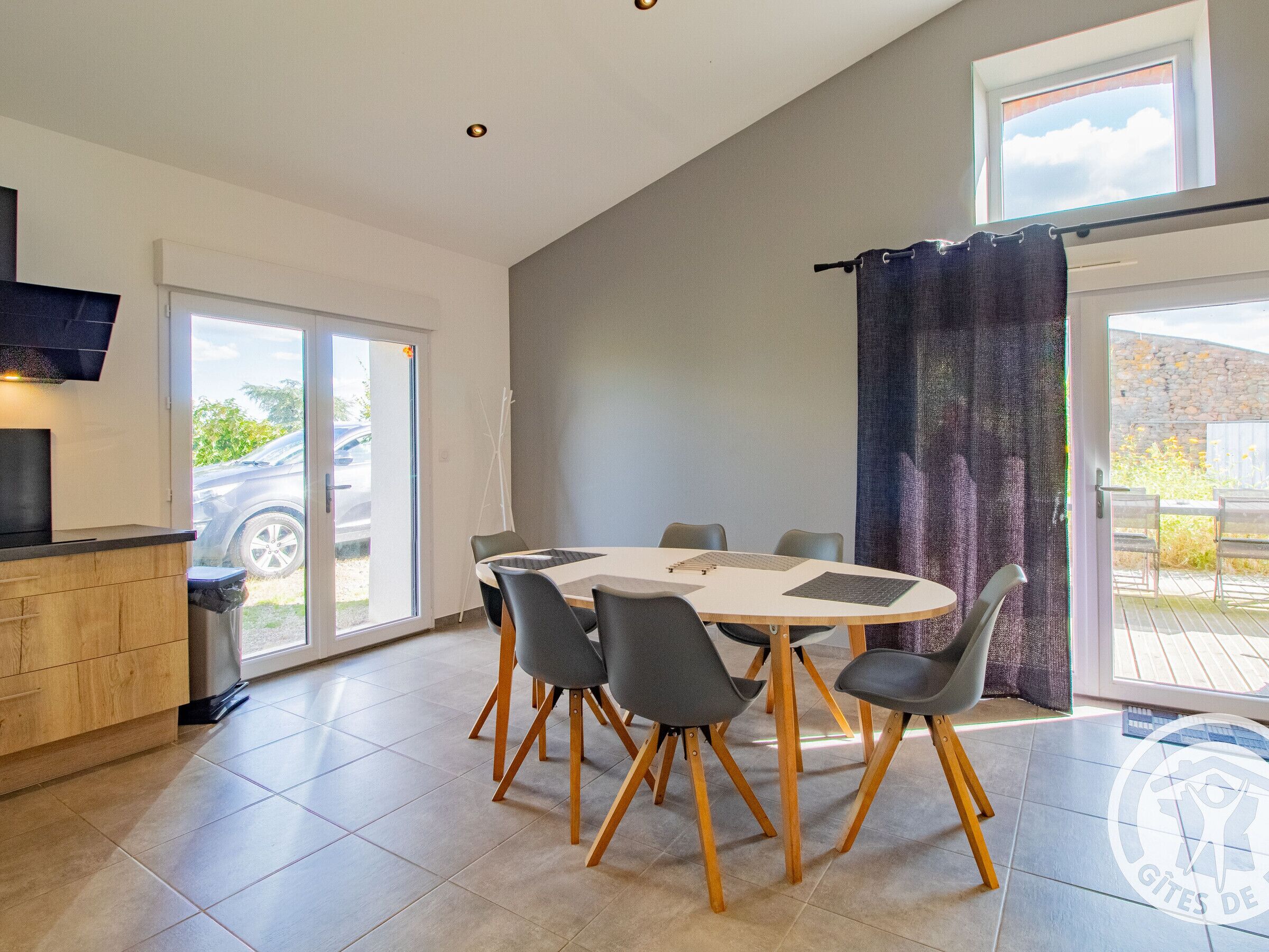 Een moderne eetruimte met een ronde tafel, zes stoelen en een houten kast.