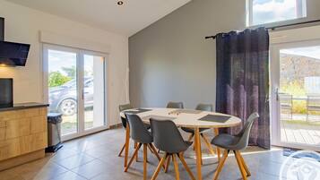 Een moderne eetruimte met een ronde tafel, zes stoelen en een houten kast.