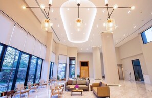 A spacious lobby with large windows, a reception desk, and modern lighting fixtures. - Centara Life Wisma Hotel Ratchaburi (Ratchaburi)