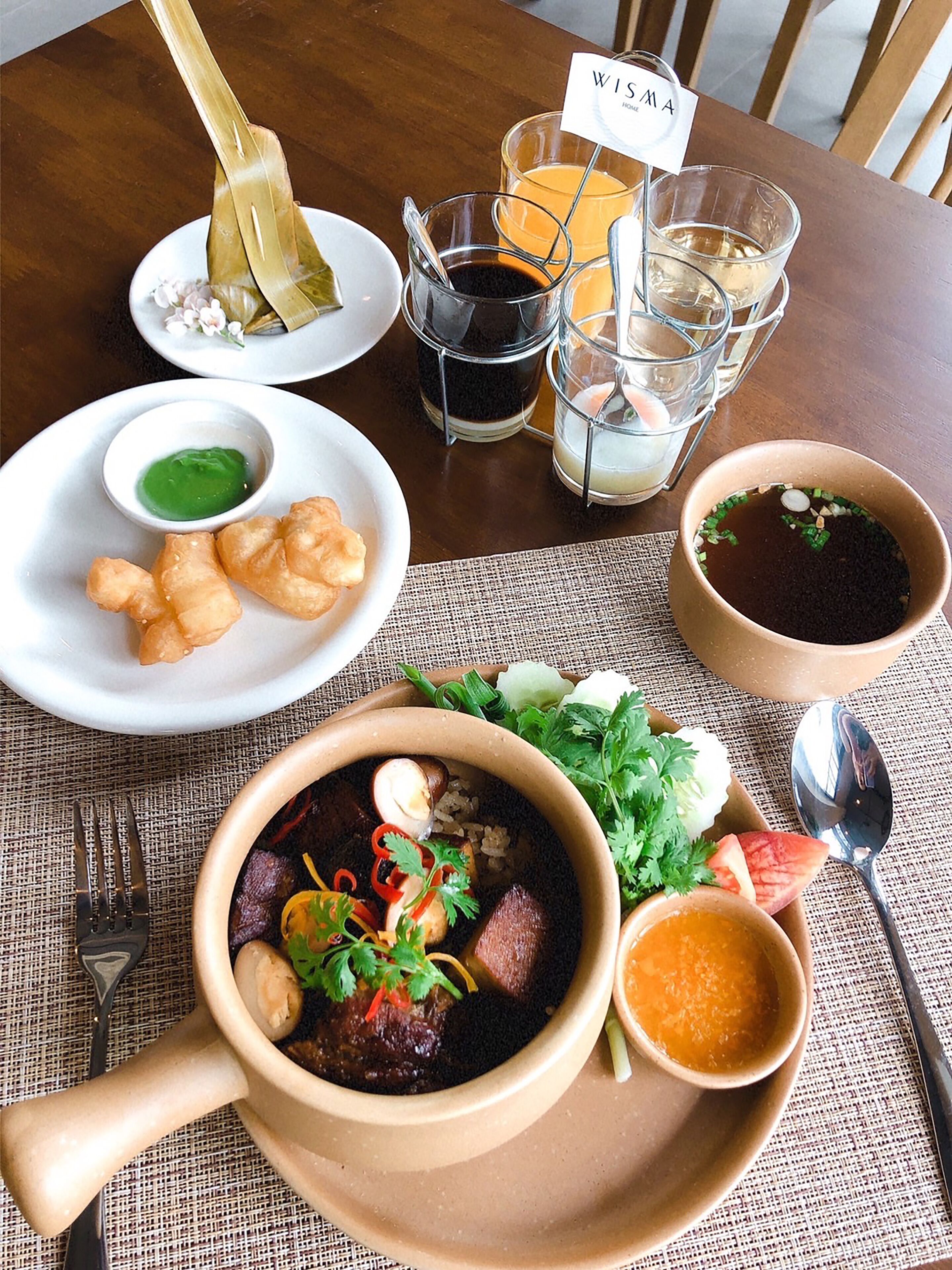 A table with a bowl of soup garnished with herbs, a plate of fried items, and a small bowl of green sauce.