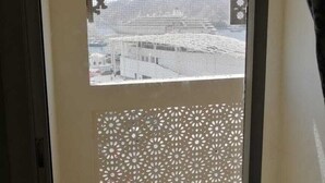 Una habitación con vistas a través de una ventana con paneles decorativos, suelo de baldosas y techo con vigas a la vista.
