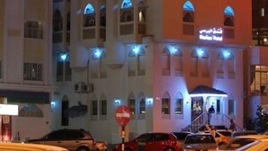 Un hotel con un letrero llamativo que dice 'Marina Hotel' y texto en árabe encima.