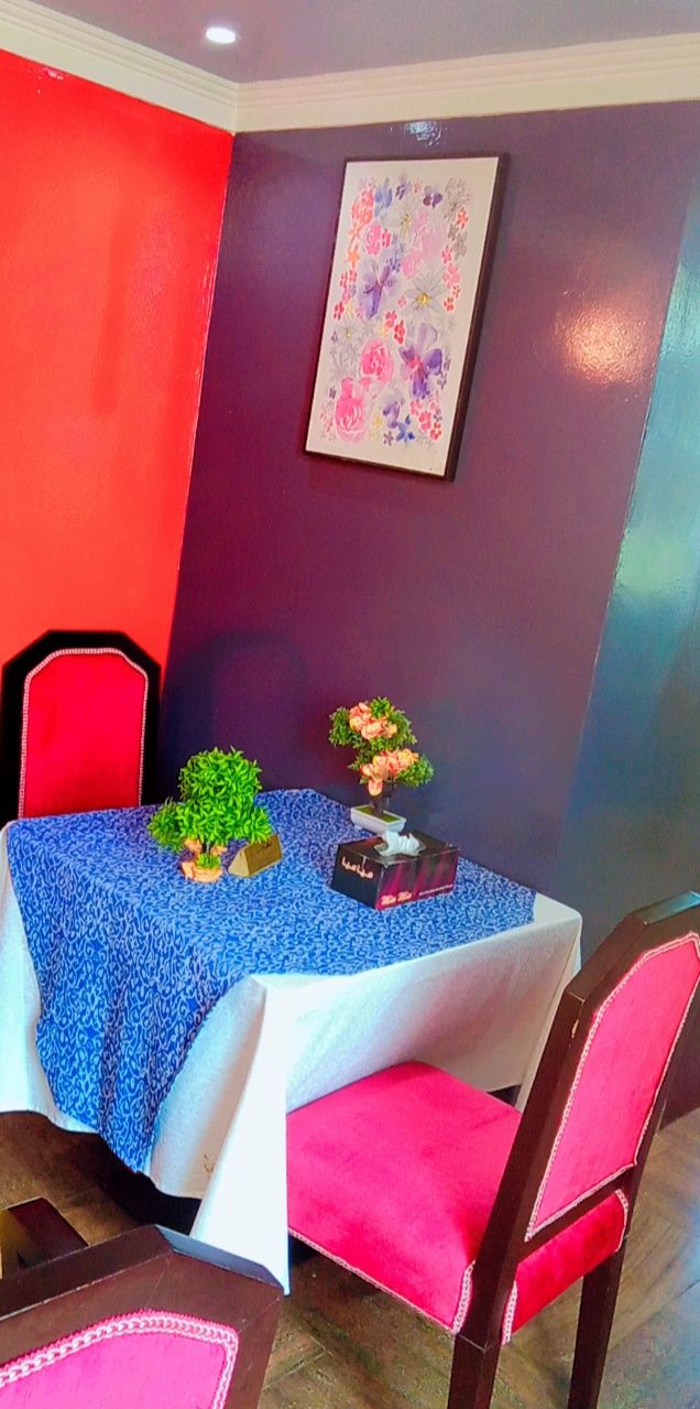 A dining area with a table set for four, surrounded by chairs.