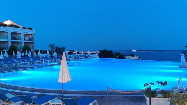 Ein großer, leerer Swimmingpool mit Liegestühlen und Sonnenschirmen rundherum.