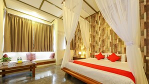A bedroom with a bed, a bedside table, a window with curtains, a wooden floor, and a wall with a patterned design. - Collection O Ivory Hotel & Resort (Rawang)