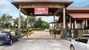 A hotel entrance with a covered area, a sign for Ivory Hotel & Resort, and a parking lot with cars. - Collection O Ivory Hotel & Resort (Rawang)
