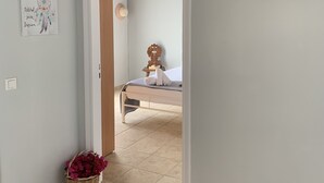 Een gang die leidt naar een slaapkamer met een bed, een wandairconditioner en een lijst met een afbeelding.
