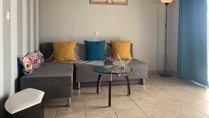 Een woonkamer met een bank, twee kussens, een glazen salontafel en een vloerlamp.