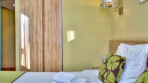 A hotel room with a bed, a wooden wardrobe, and a wall-mounted lamp. - Apartment Port Prestige (Antibes)