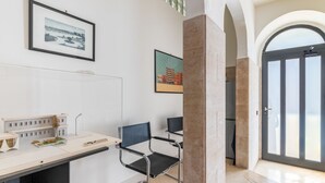 A modern interior with a desk, two chairs, framed pictures on the wall, and a door leading to an outdoor area. - GuestHost - Functional apartment ideal for two people and equipped with the main services for a comfortable stay. The flat is located 7 minutes walk from the Central Station and 10 minutes from the Aldo Moro University and the Petruzzelli Theater, in an  (Bari)
