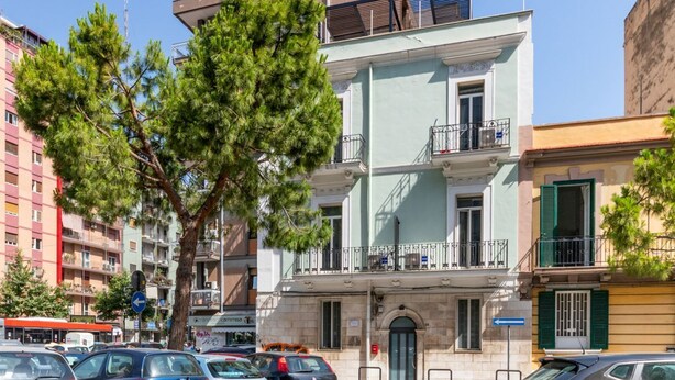 A multi-story building with balconies, parked cars, and a clear sky. - GuestHost - Functional apartment ideal for two people and equipped with the main services for a comfortable stay. The flat is located 7 minutes walk from the Central Station and 10 minutes from the Aldo Moro University and the Petruzzelli Theater, in an  (Bari)