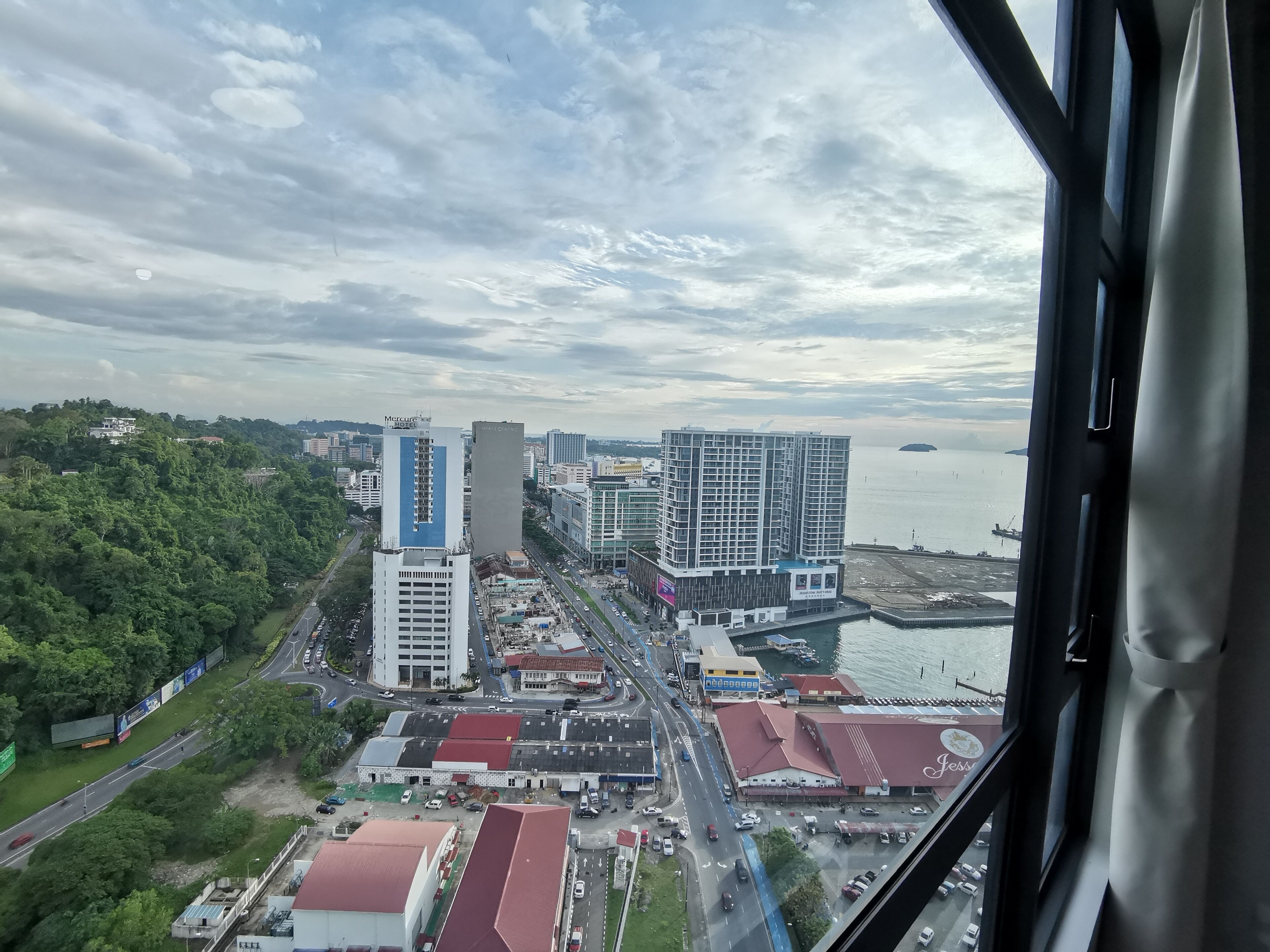 A cityscape with modern buildings, a waterfront, and a busy road.