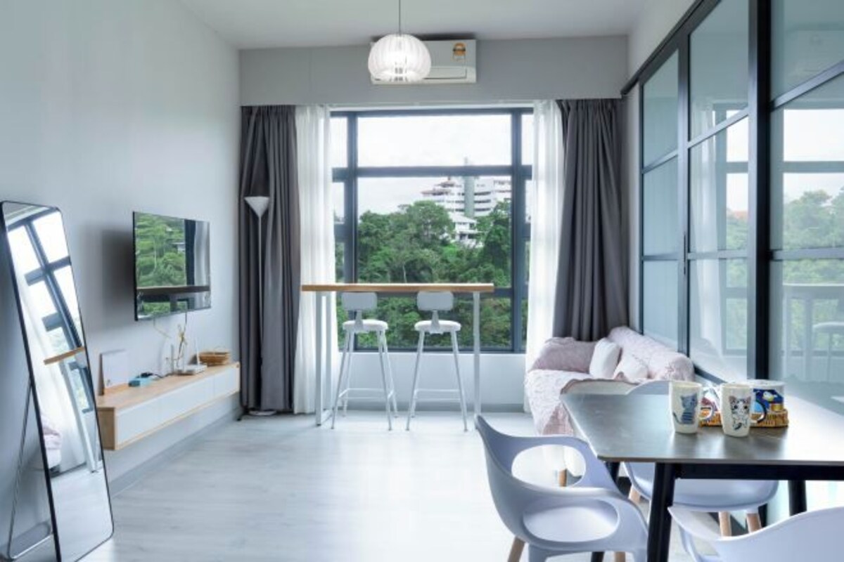 A modern living room with a sofa, a dining table, and a TV.