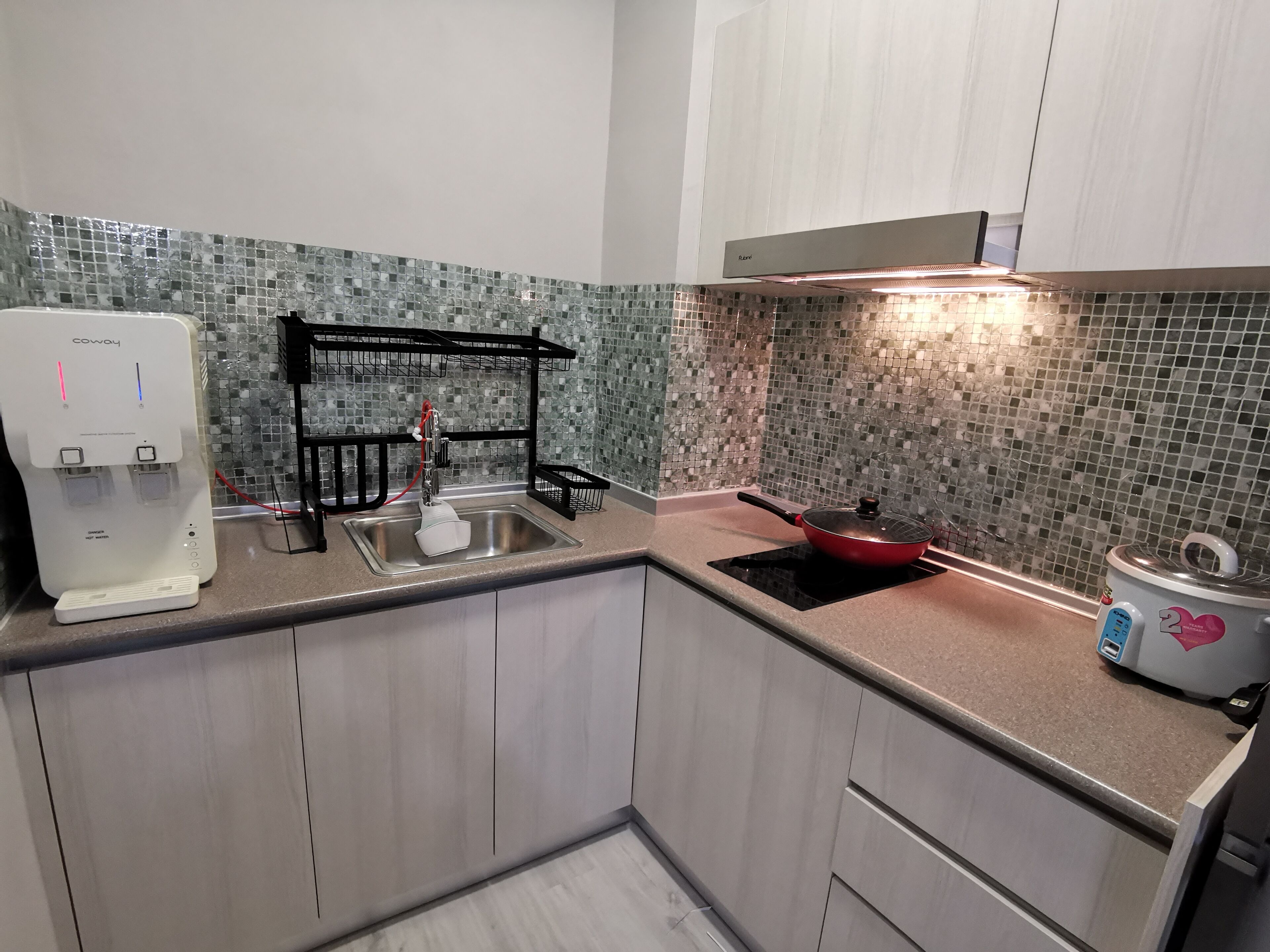 A compact kitchen with a water dispenser, a sink, a stove, and a microwave.