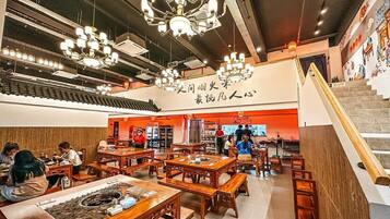 A restaurant with wooden tables and chairs, a staircase, and a sign with Chinese characters.