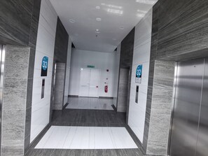Un'area ascensore moderna con pareti in marmo, pavimento bianco e segnaletica direzionale per il 32° piano.