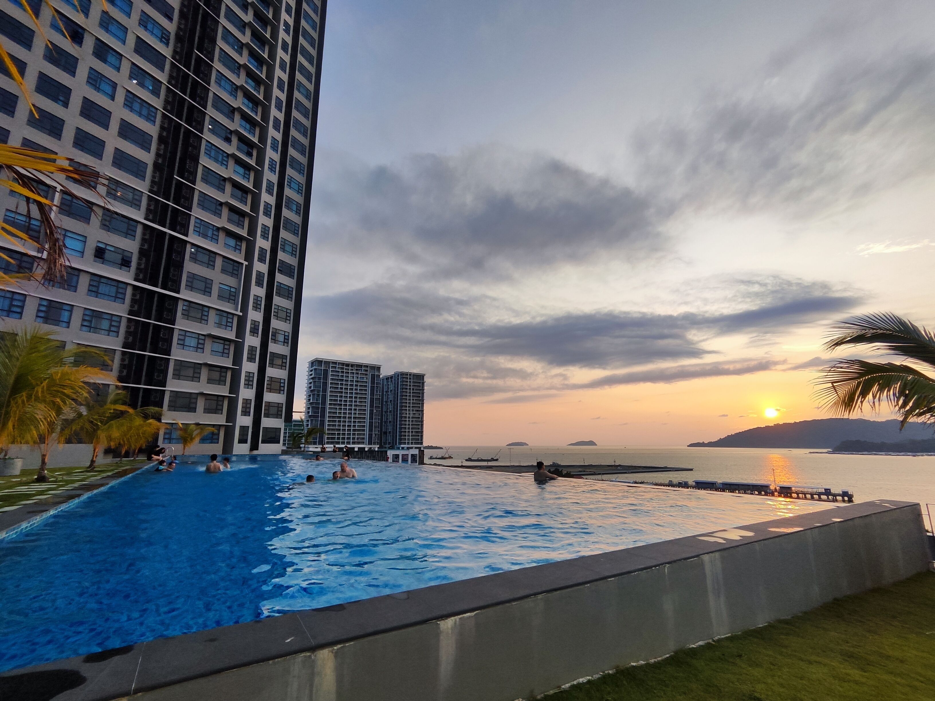 A swimming pool with a sunset view, surrounded by high-rise buildings.