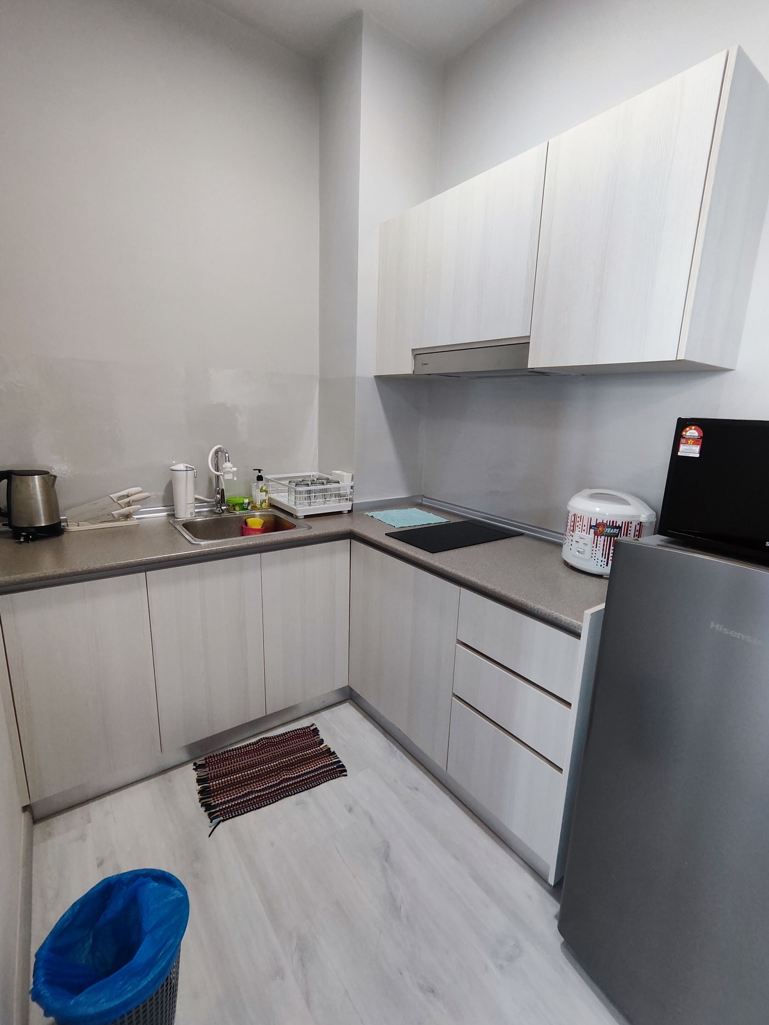 A modern kitchen with white cabinets, a stainless steel refrigerator, and a black countertop.
