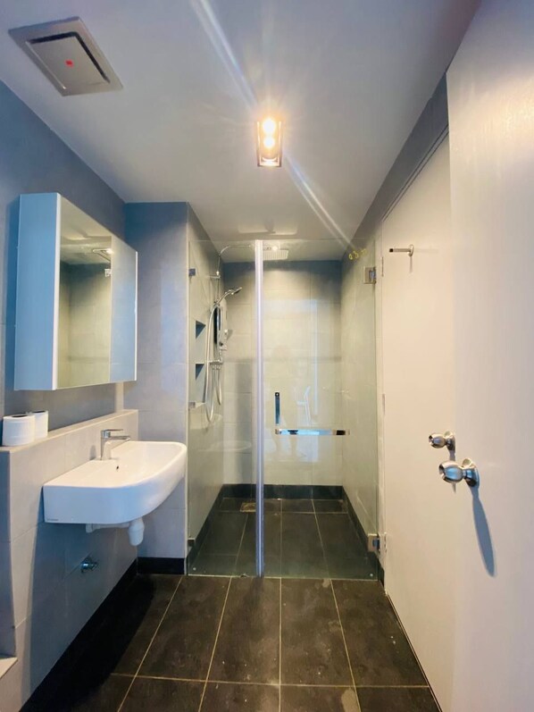 Un baño moderno con cabina de ducha de vidrio, un lavabo blanco y un espejo.