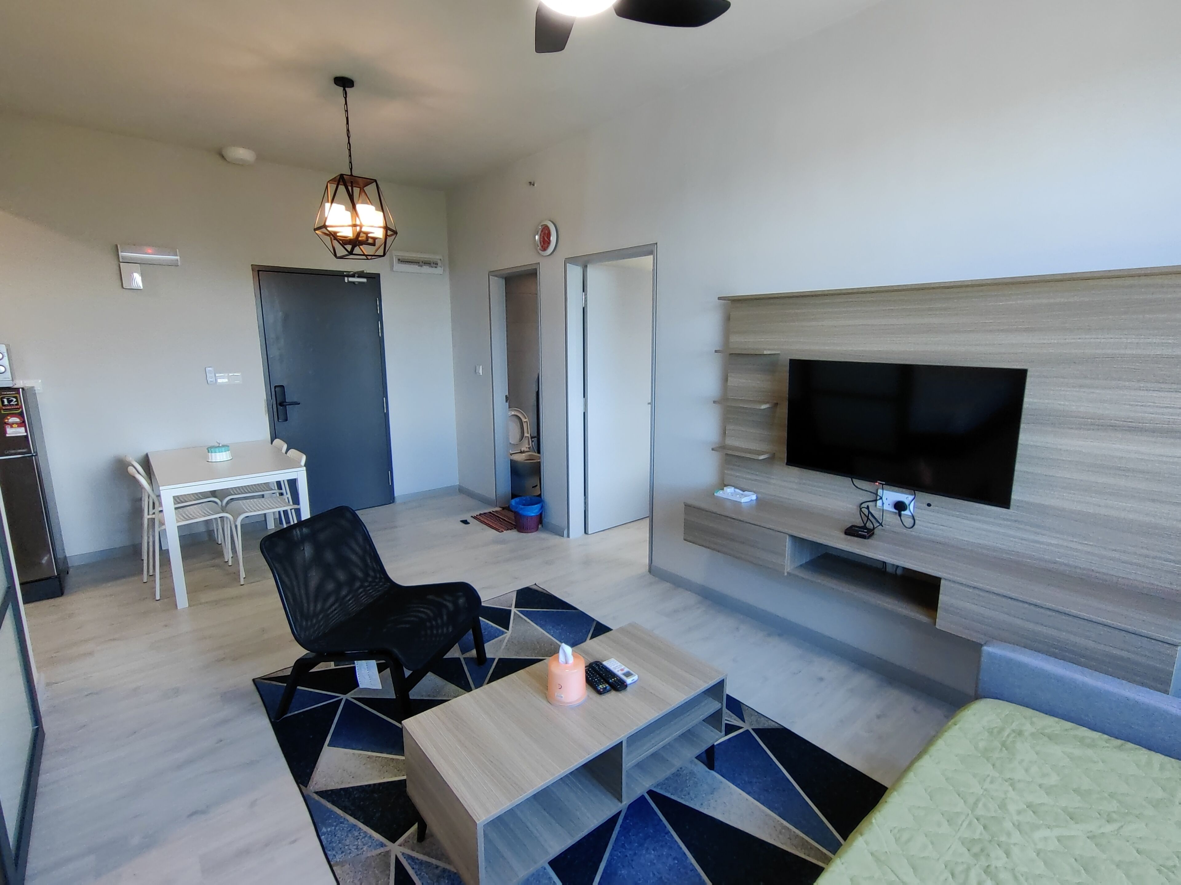 Uma sala de estar moderna com televisão, mesa de jantar e uma cadeira preta.